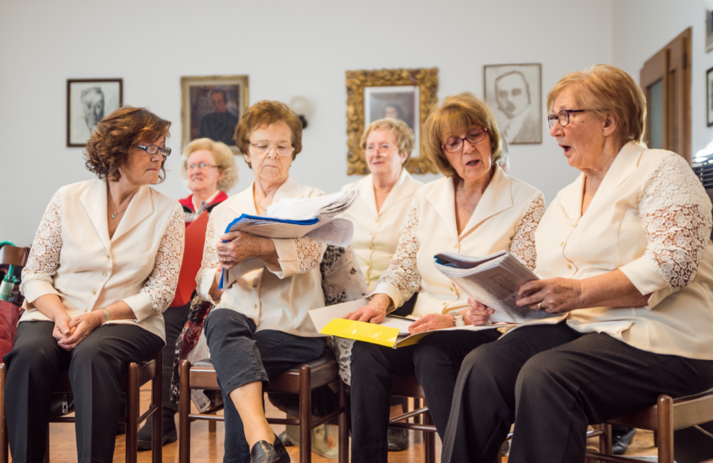 Choristes seniors en r&eacute;p&eacute;tition, partitions ouvertes sur les genoux